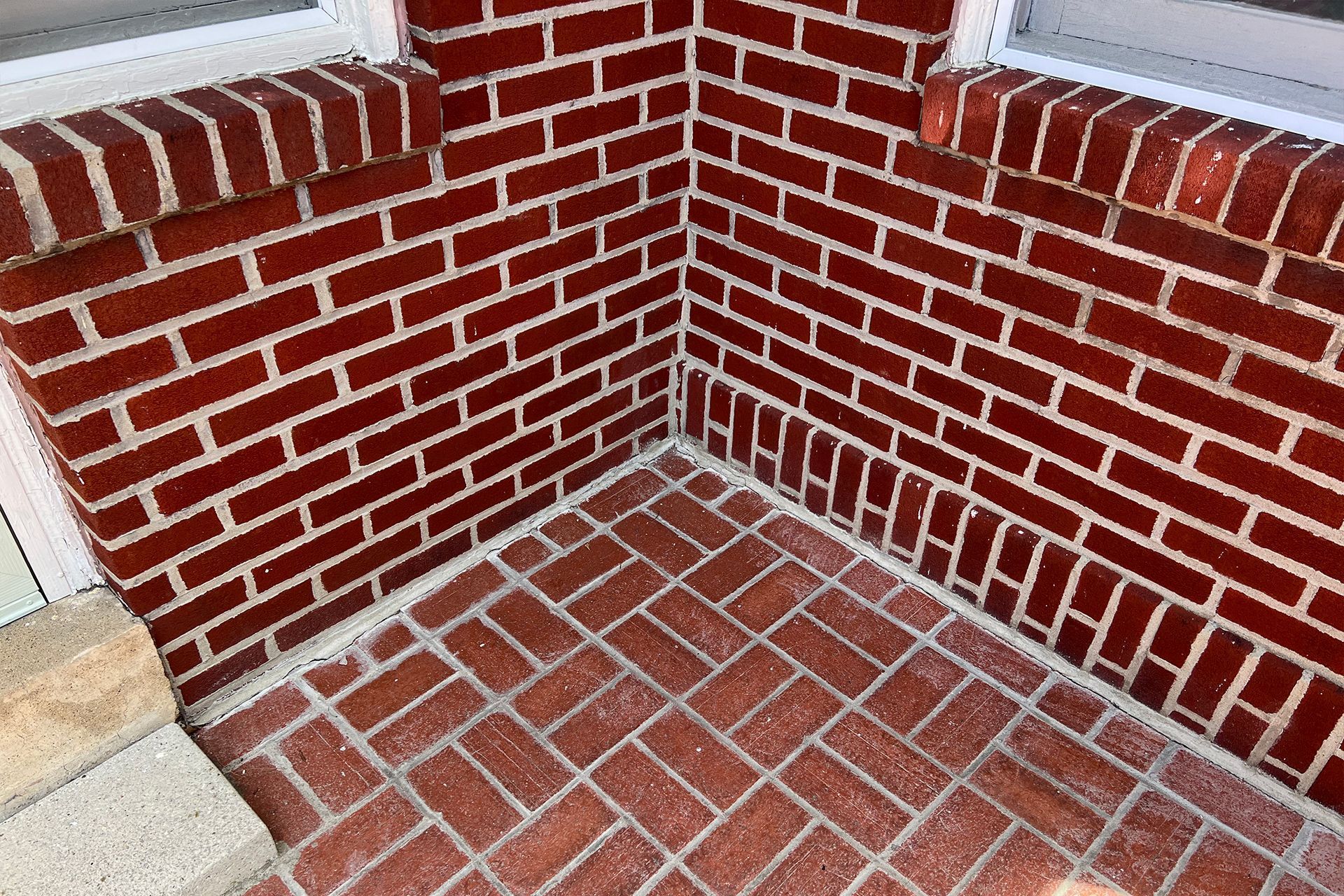 Red brick corner with herringbone brick floor, white window frame.