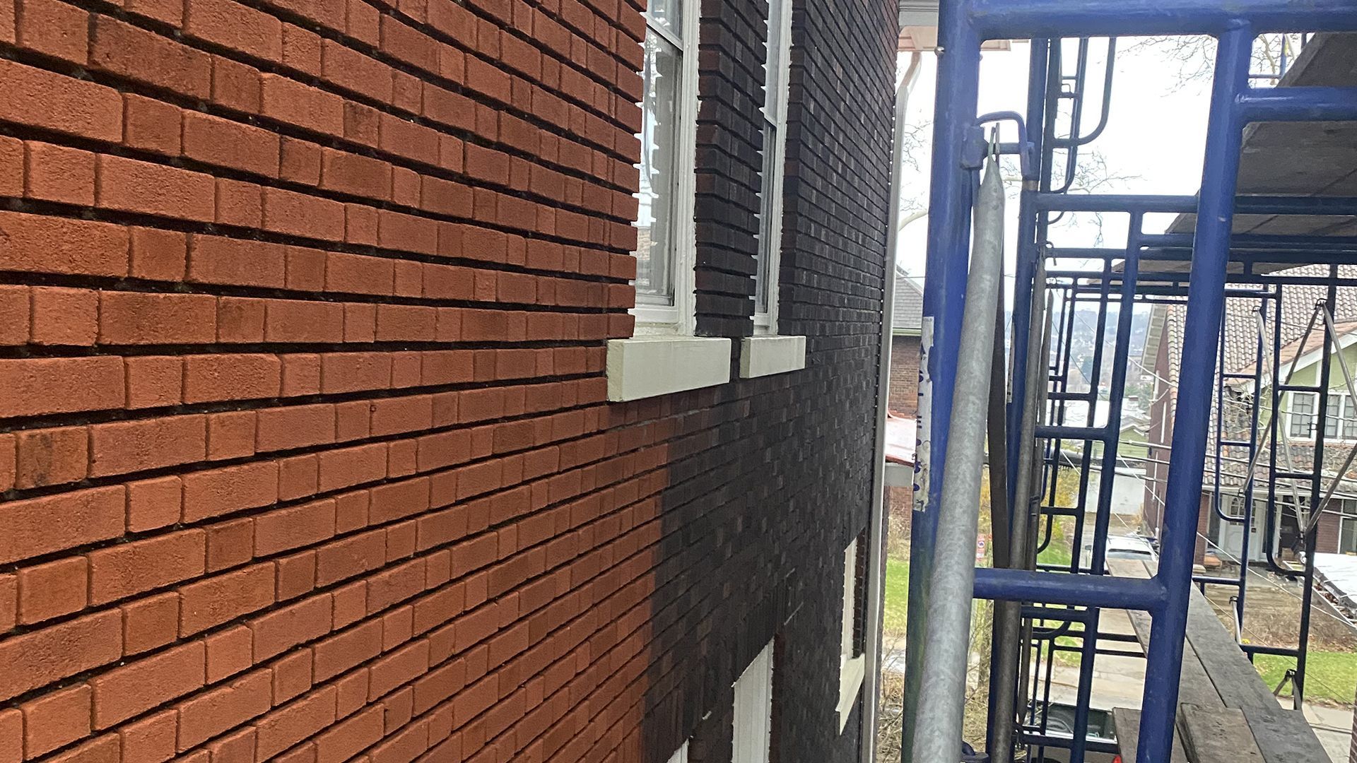 Brick wall of a building with a window and scaffolding on the right.