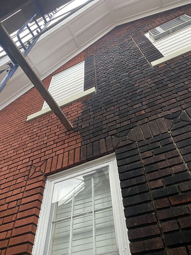 Brick wall partially cleaned, showing contrast between original dark color and bright red after cleaning.