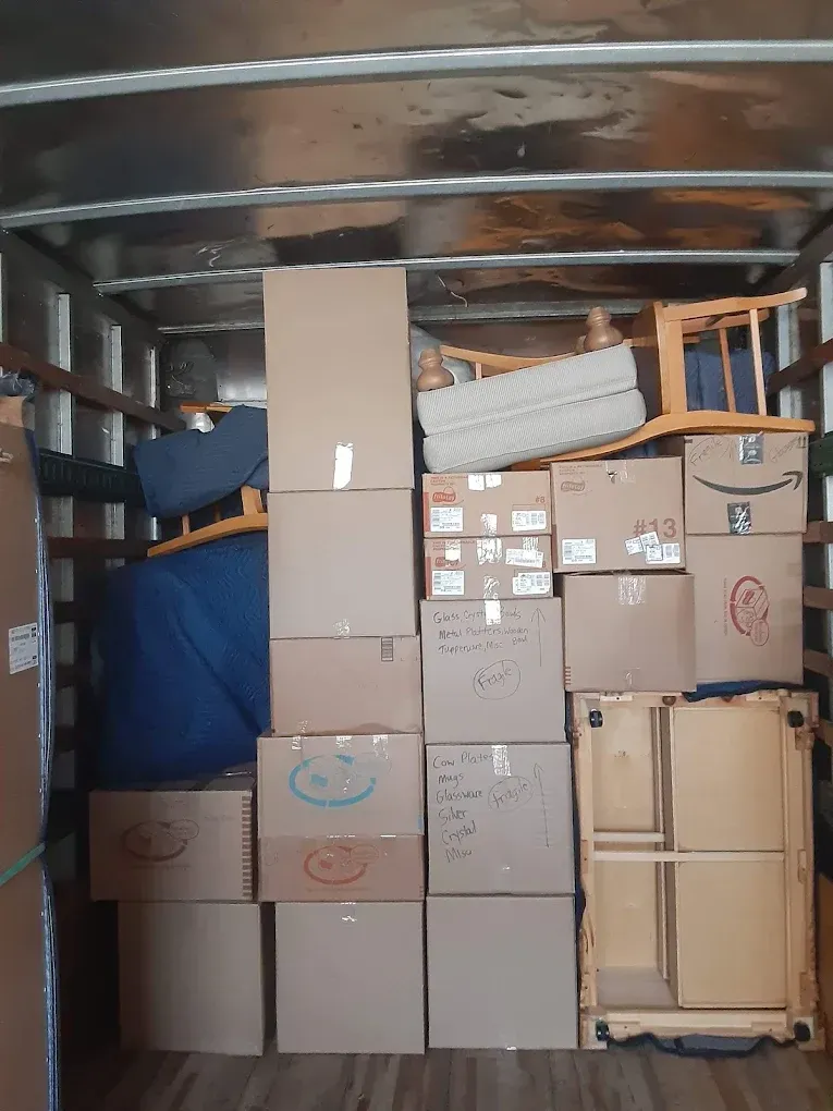 Boxes and furniture loaded inside a moving truck, ready for transport.