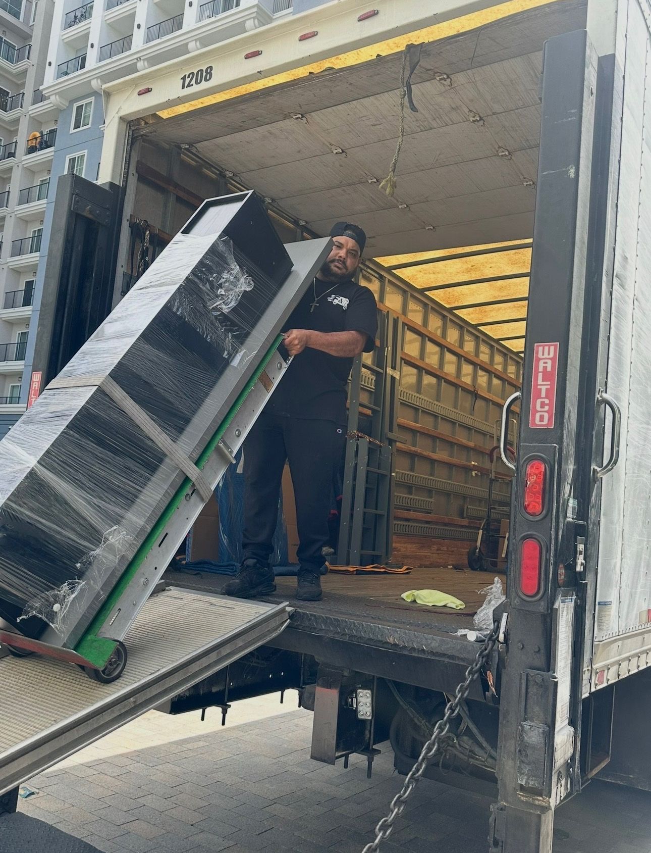 A person unloading a large, wrapped item from a moving truck.