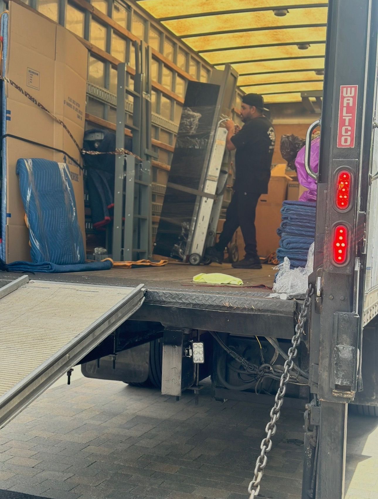 Workers loading furniture into a moving truck with the ramp down.