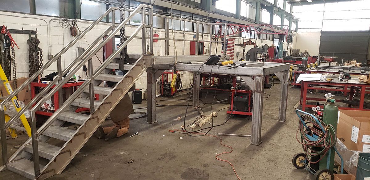There are stairs leading up to a platform in a factory.