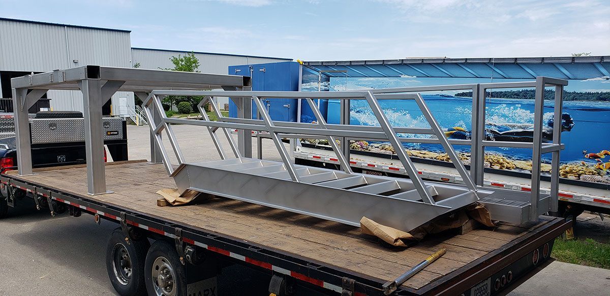 A flatbed truck is carrying a staircase made of stainless steel.