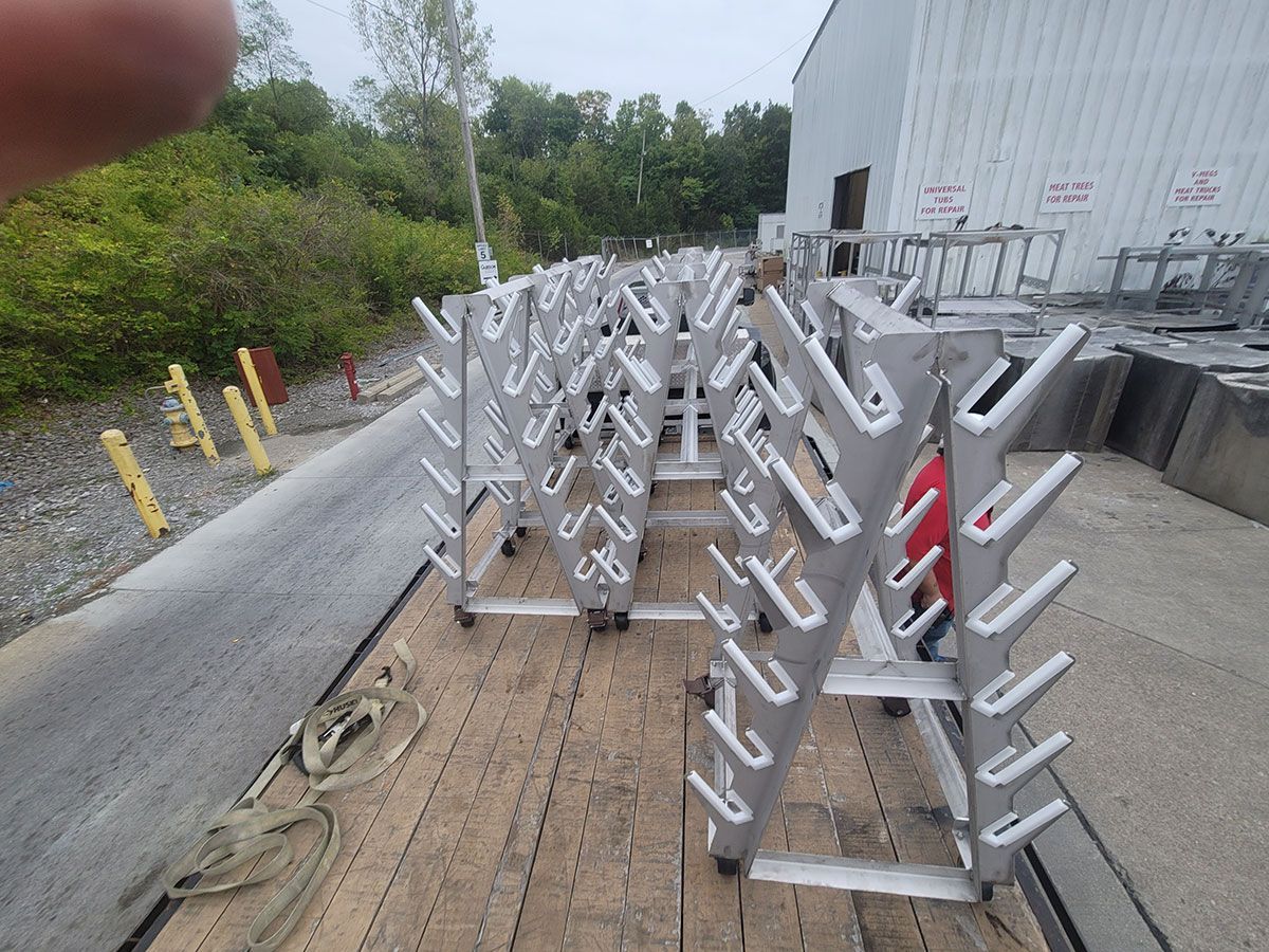 A row of dumbbell racks are sitting on top of a wooden trailer.