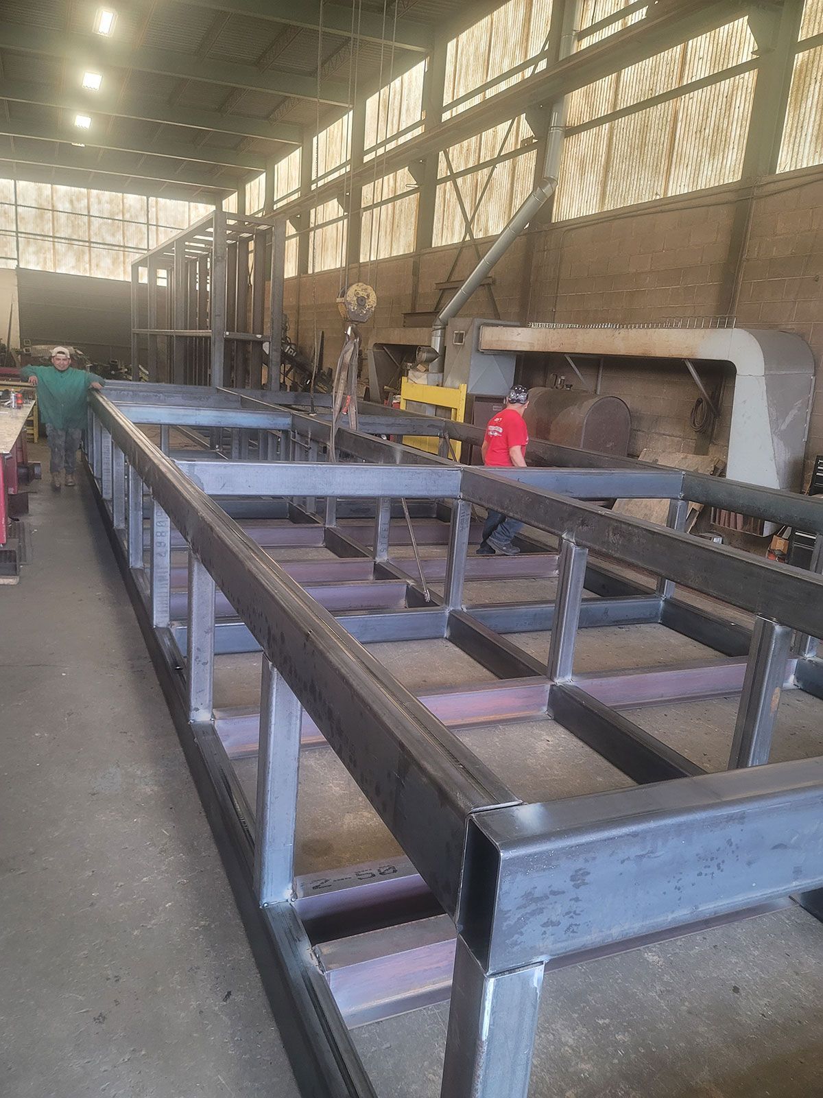 A large metal structure is being built in a factory.