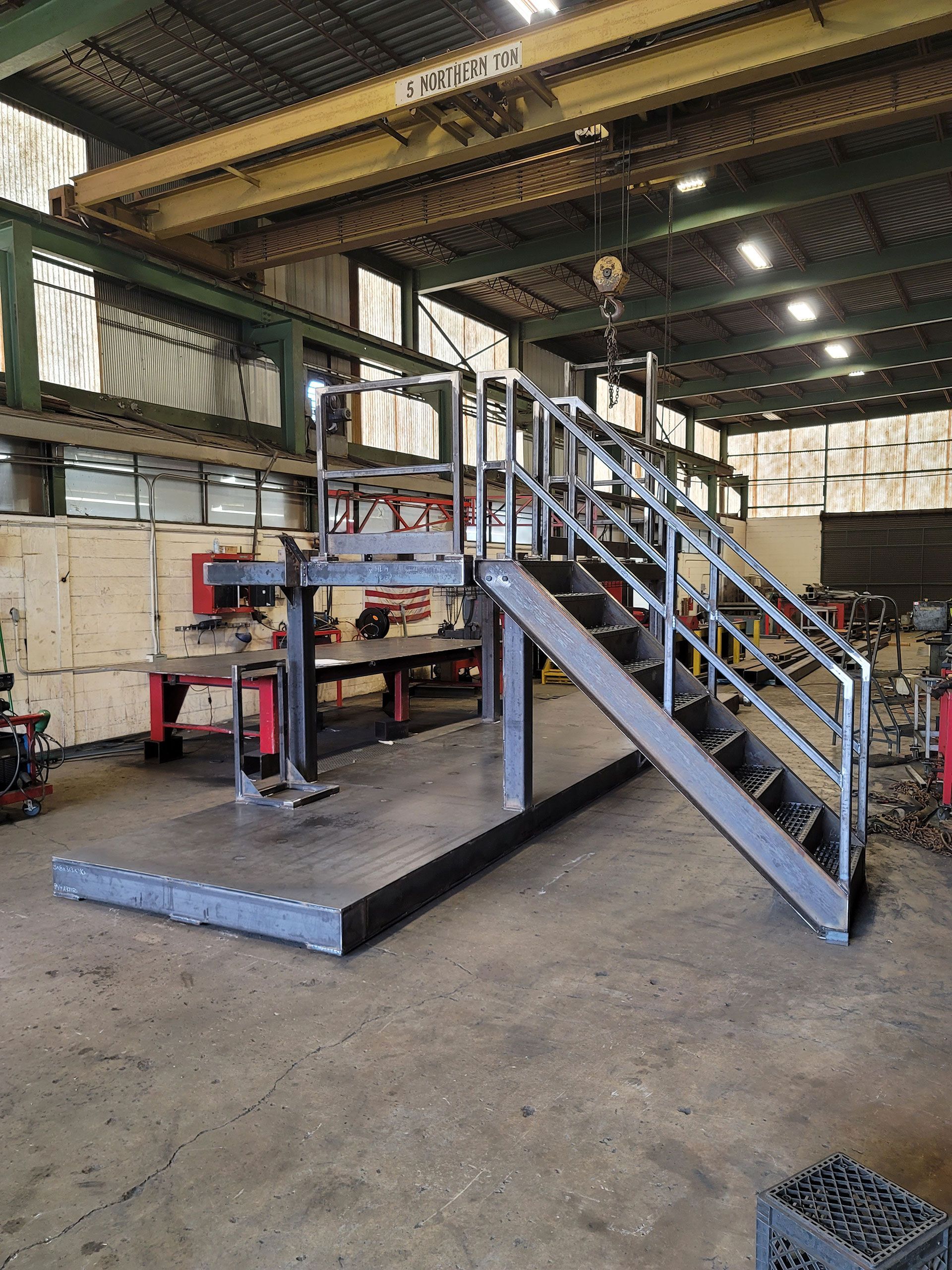 A metal staircase is being built in a factory.