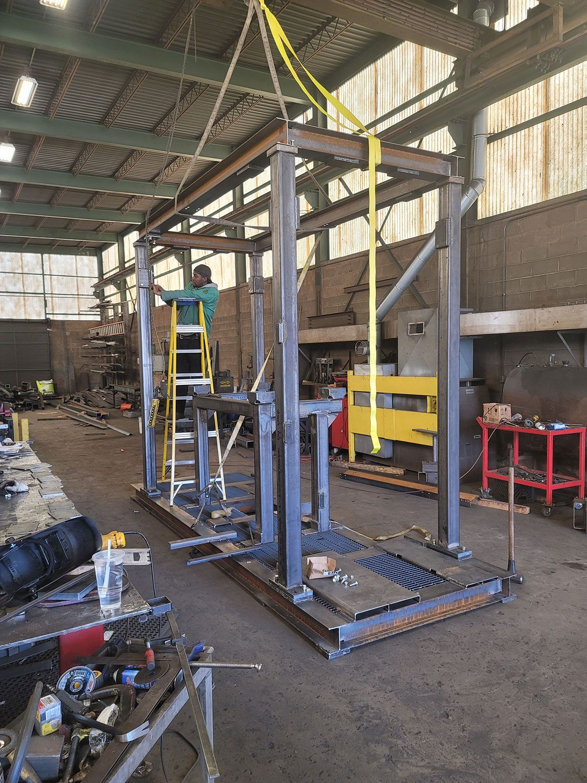 A man is standing on a ladder in a factory.