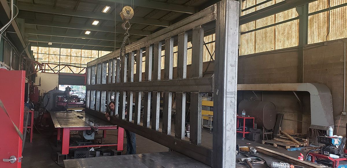 A large metal structure is being built in a factory.