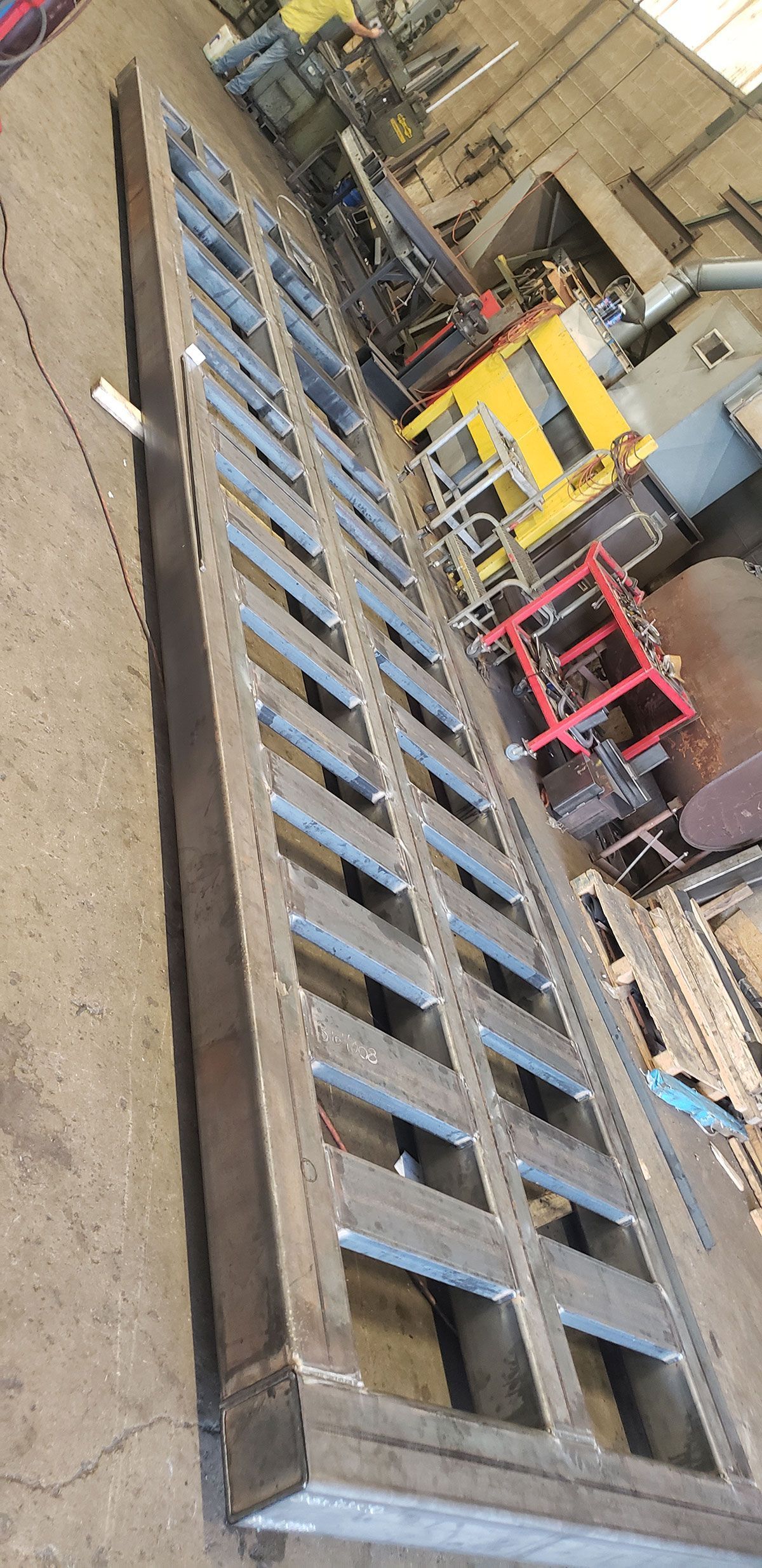A large metal structure is sitting on top of a cement floor in a factory.