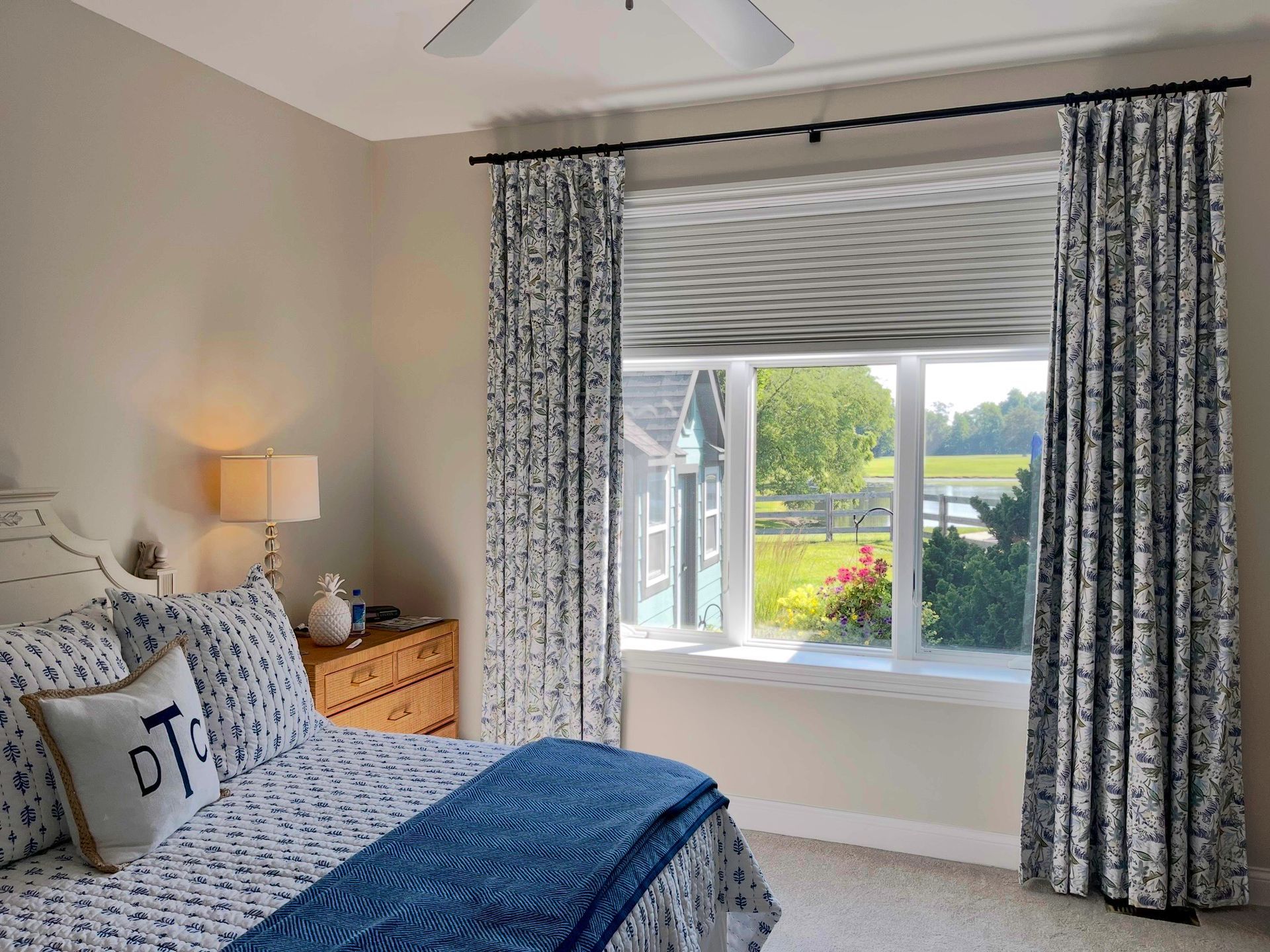A bedroom with a bed, dresser, lamp, and window.