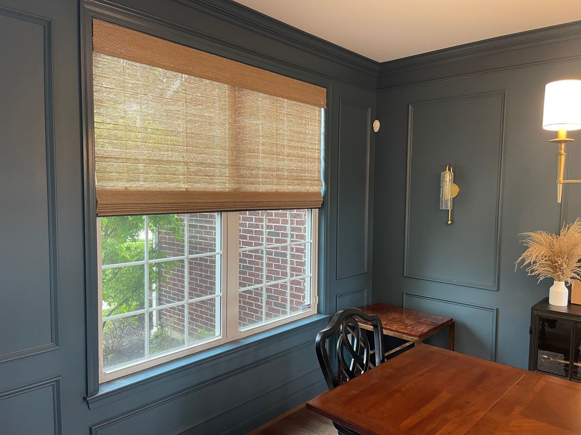 A dining room with a wooden table and chairs and a large window.