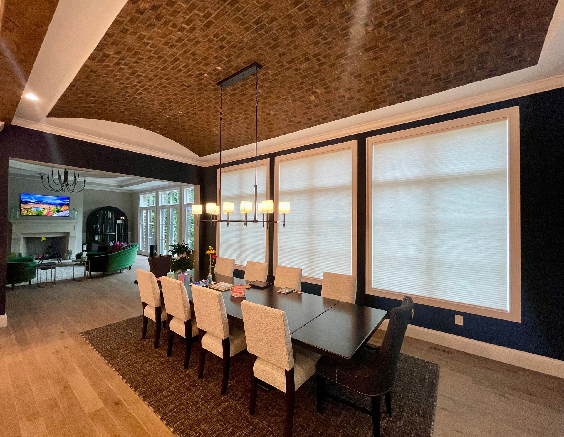 A dining room with a long table and chairs and a chandelier hanging from the ceiling.