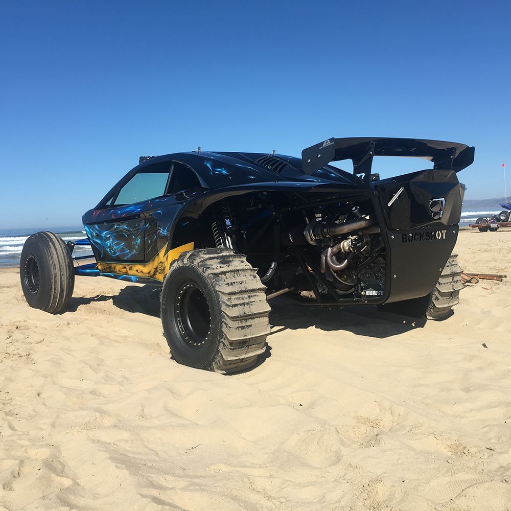 A blue atv is driving through the sand on a dirt road.