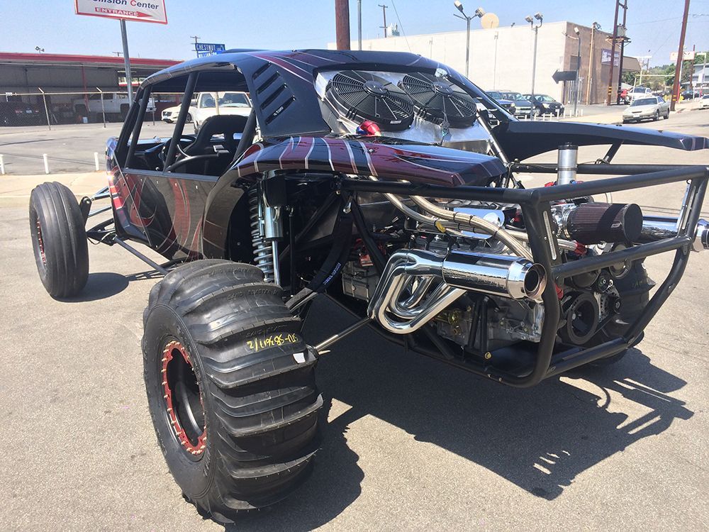A monster truck is parked in a parking lot in front of a building.