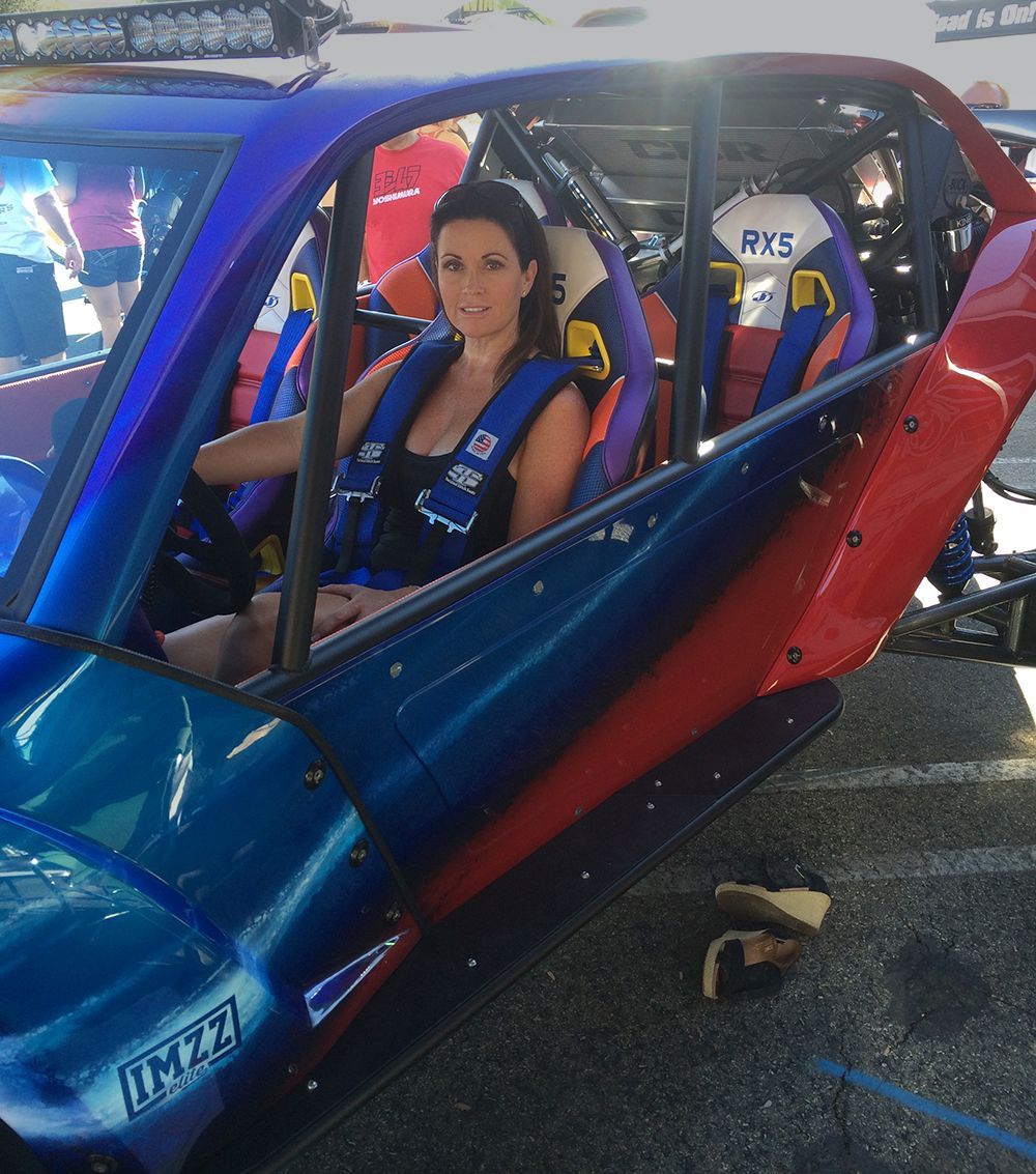 A woman is sitting in a blue and red vehicle.