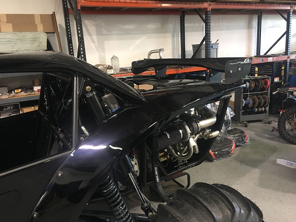 A black vehicle is being built in a garage.