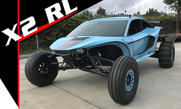 A blue x2 rl buggy is parked in a parking lot.