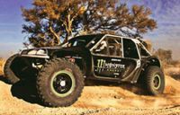 A monster energy off road vehicle is driving down a dirt road.