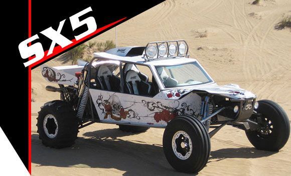 A white sx5 buggy is parked in the sand.