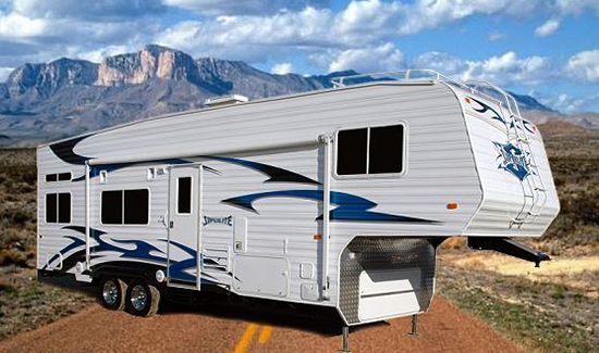 A white and blue trailer is parked on the side of a dirt road.