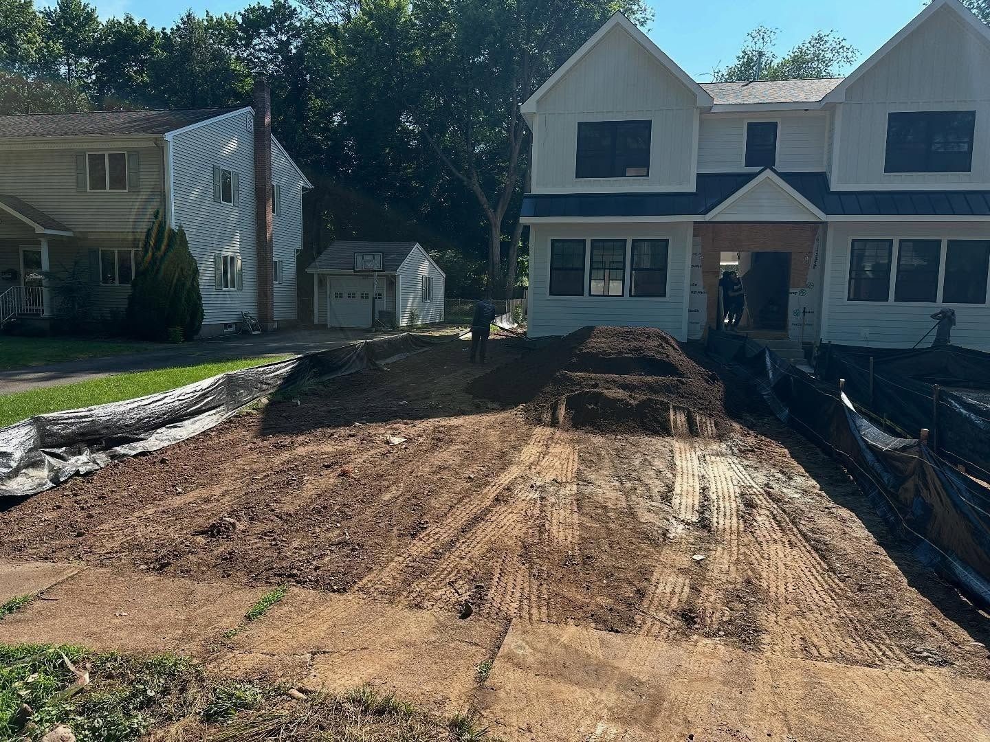 Construction site with brown soil, new white houses, and a small shed.