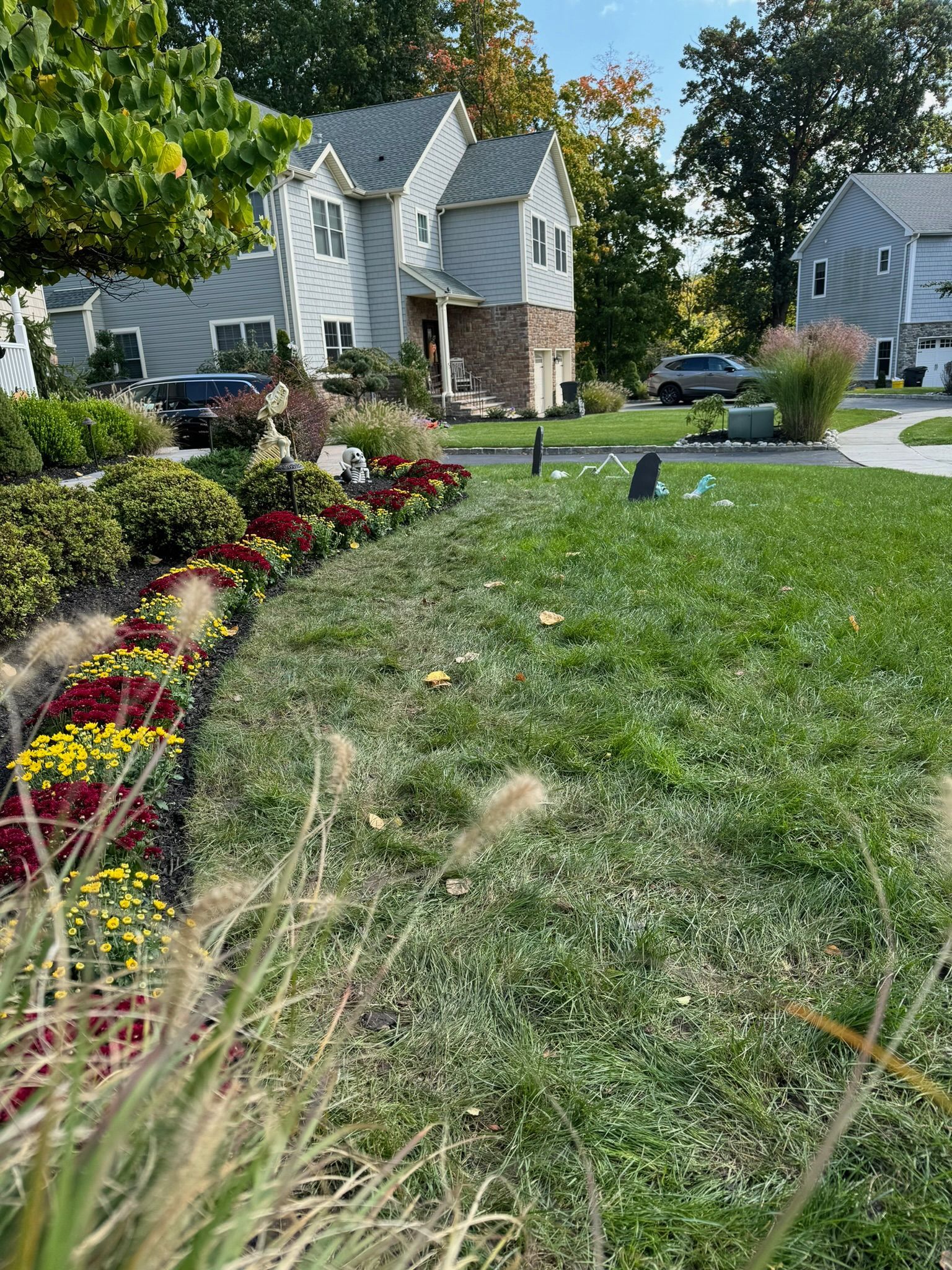 Suburban house with a grassy lawn and colorful flower beds.