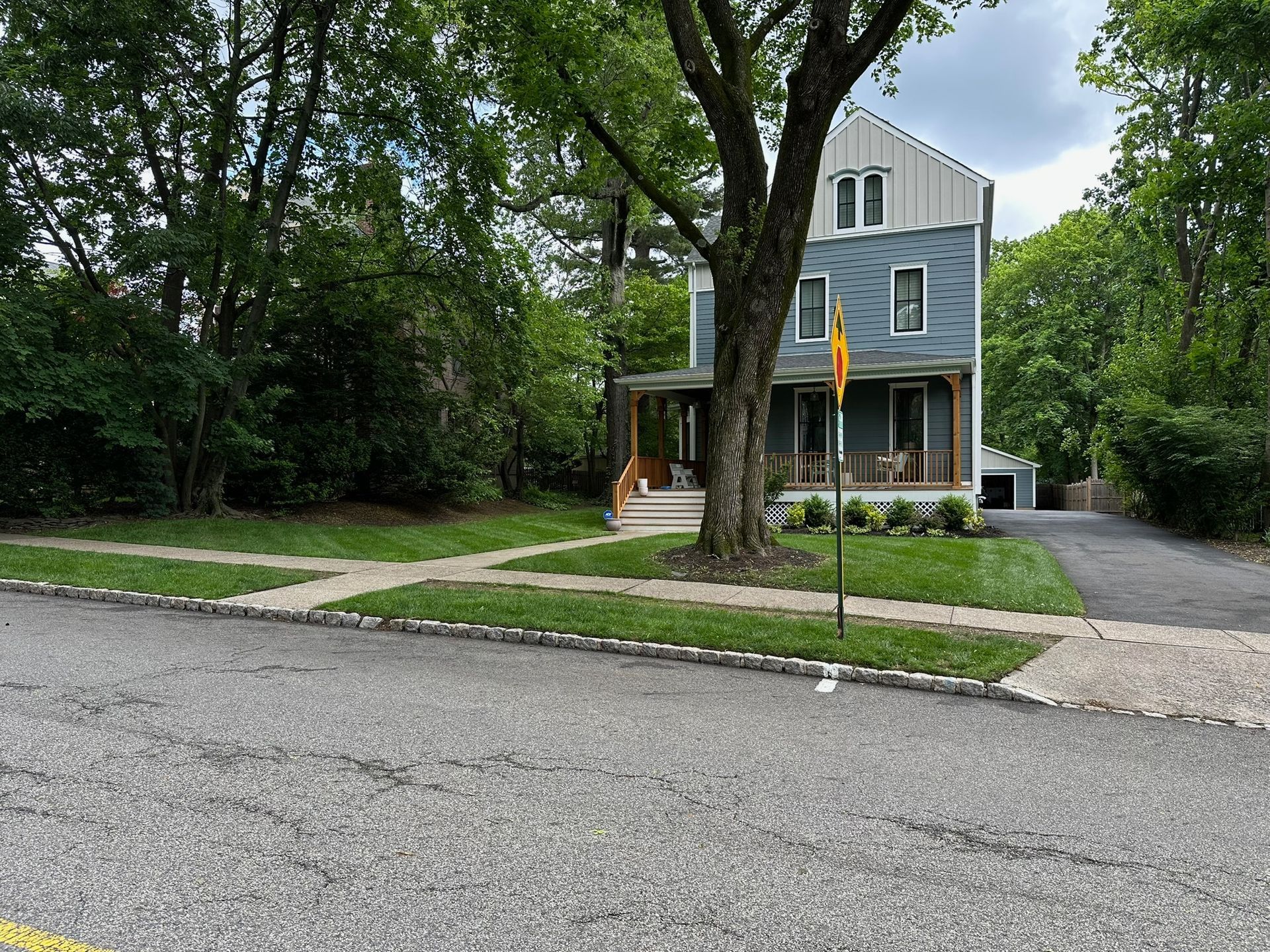 Blue and white three-story house with a porch and driveway, a tree in the yard.