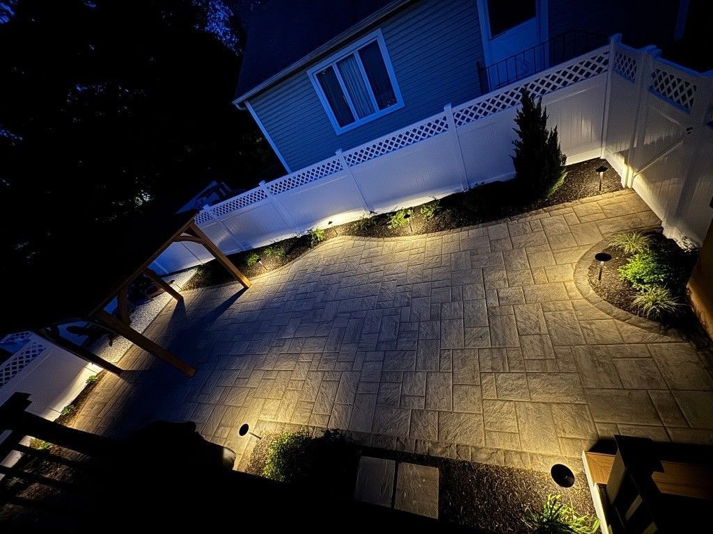 Blue house at night with lit stone walkway and yard lights, viewed from above