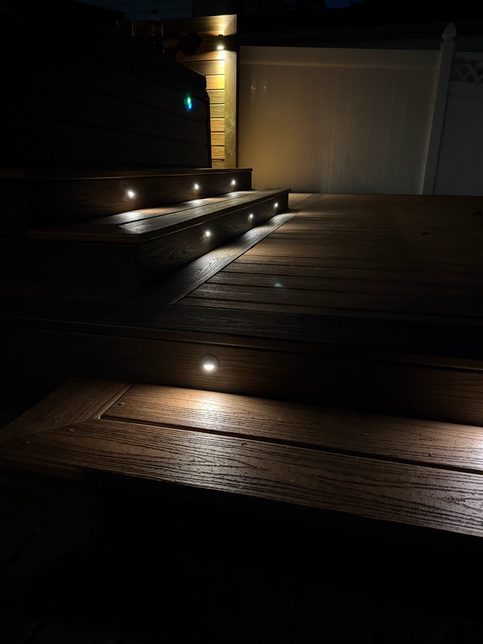 Dimly lit driveway with steps, recessed lights, and a closed garage door at night