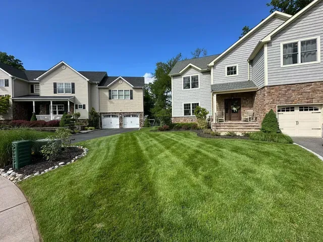 Suburban townhouses with manicured green lawns and a clear blue sky