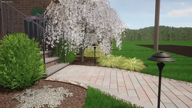 Garden patio with pink flowering tree, brick steps, green shrubs, and a black path light.