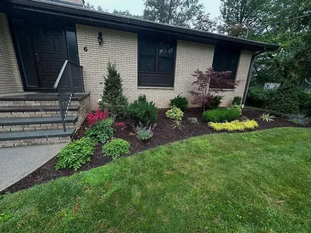 Front yard landscaping with colorful flowers and shrubs along a house exterior