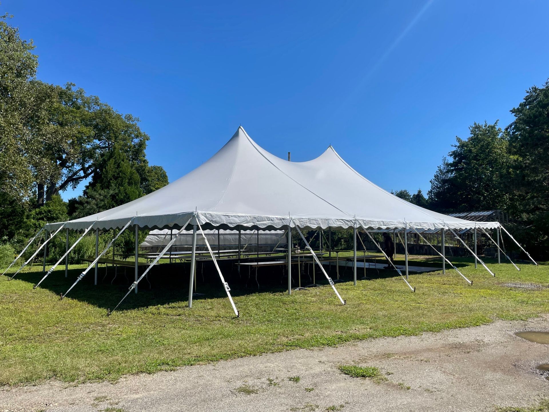 Large white event tent on a grassy field under a clear blue sky