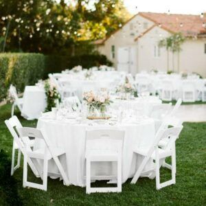 White-clothed outdoor banquet tables and chairs set up on a lawn for an event
