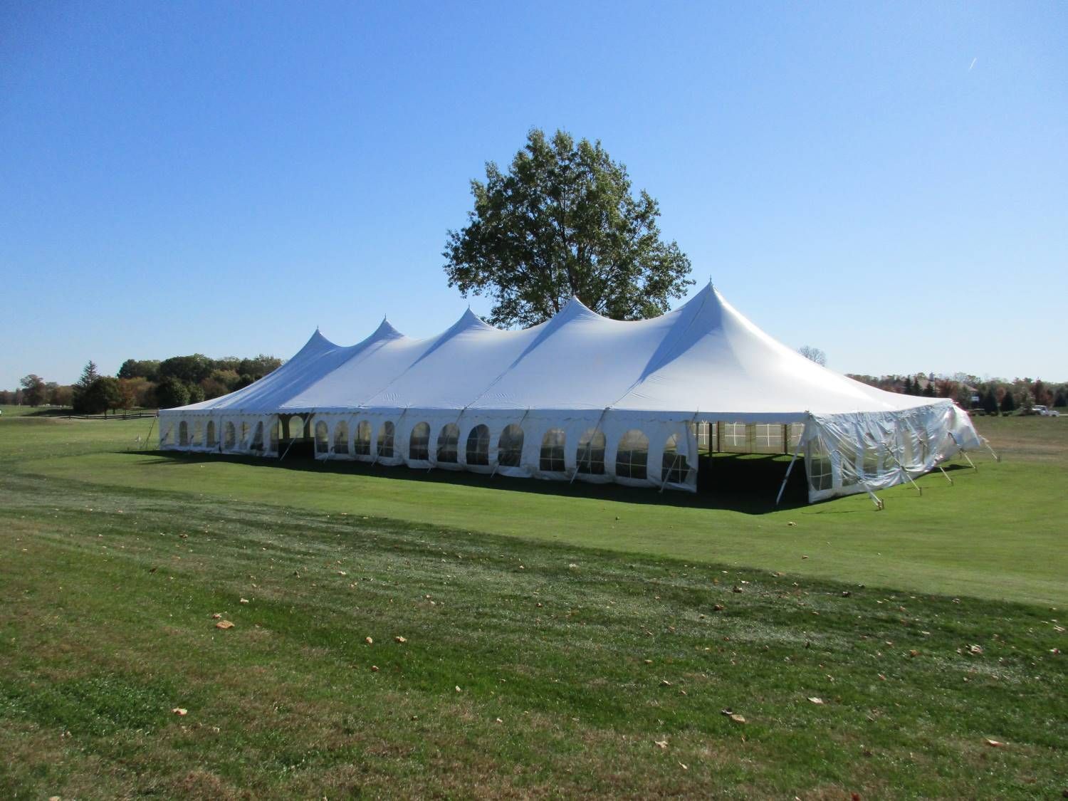 White event tent on a grassy field under a clear blue sky