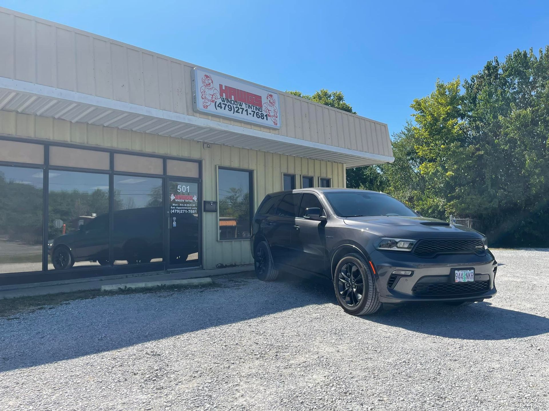 A dark gray SUV parked in front of a business with a sign.
