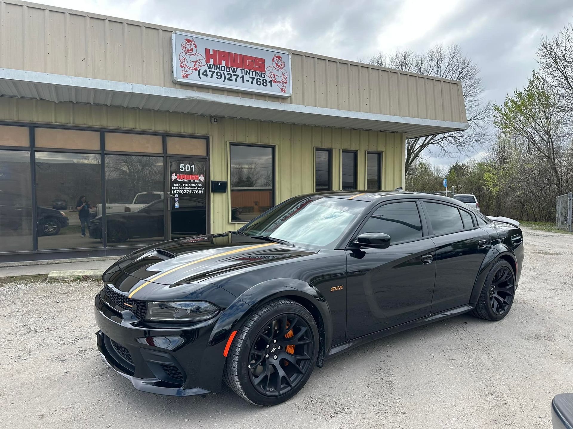 Black Dodge Charger parked in front of a commercial building with a sign above the door.