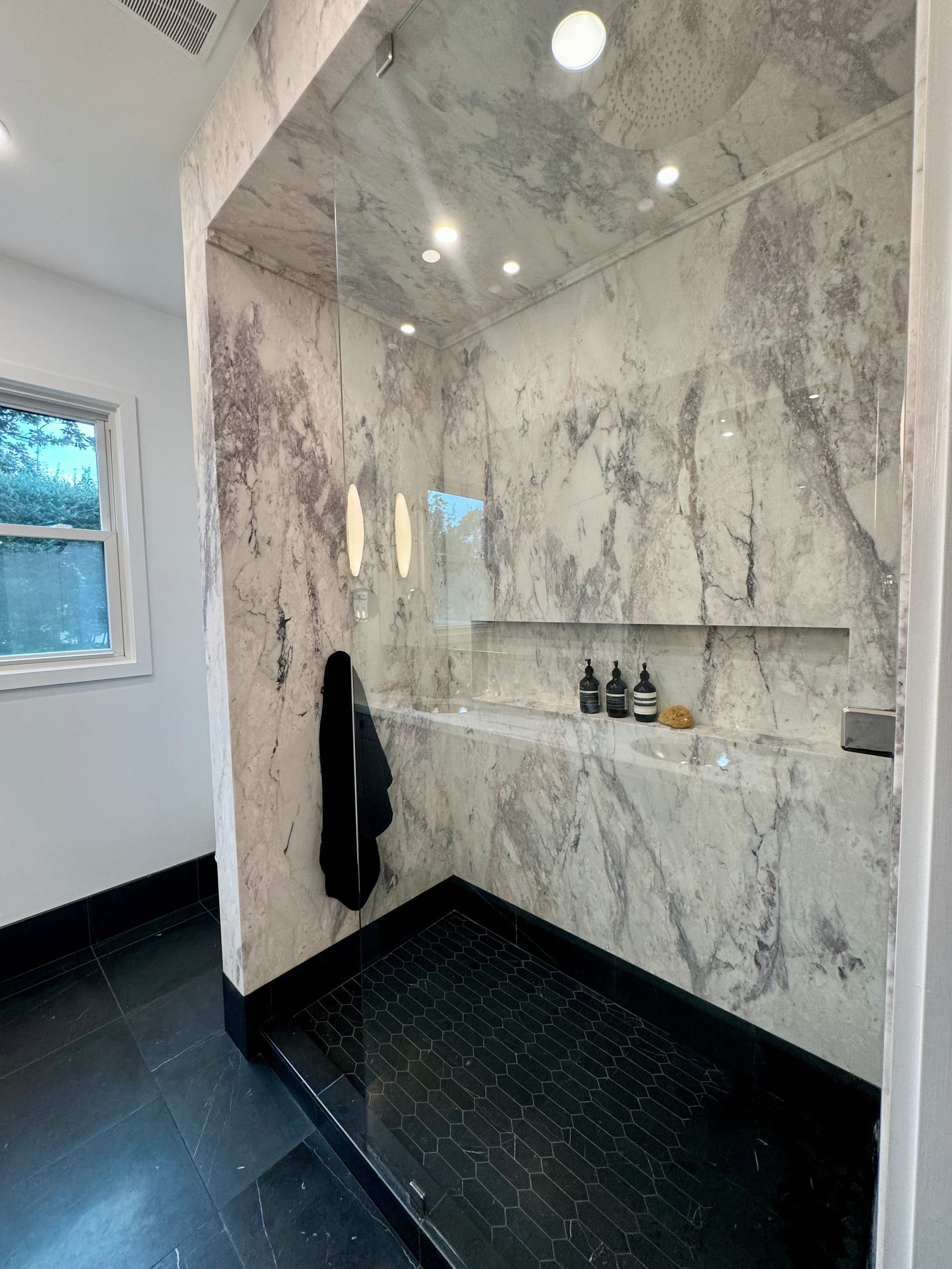 A bathroom with marble walls and a walk in shower.