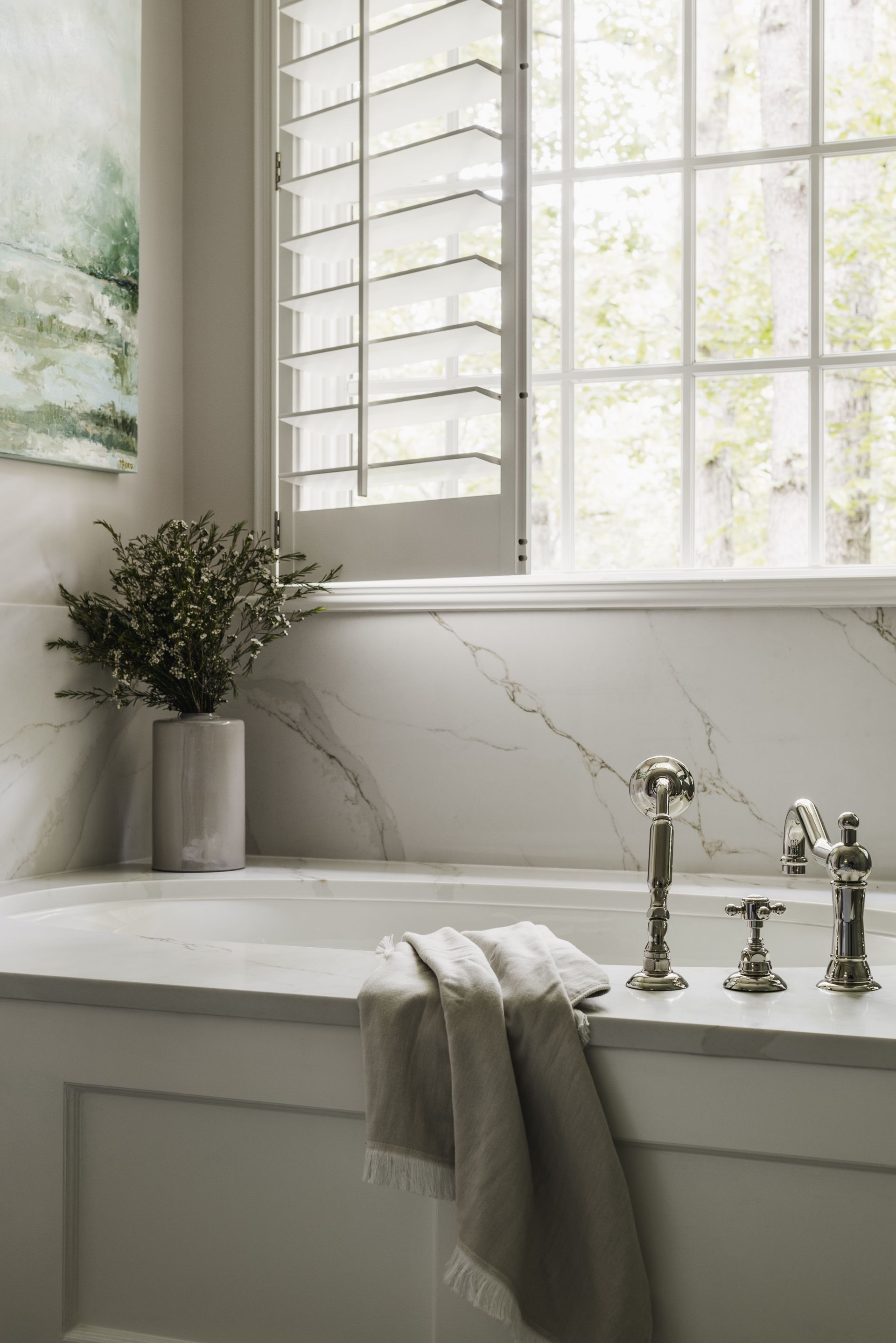 A bathroom with a bathtub and a window with shutters.