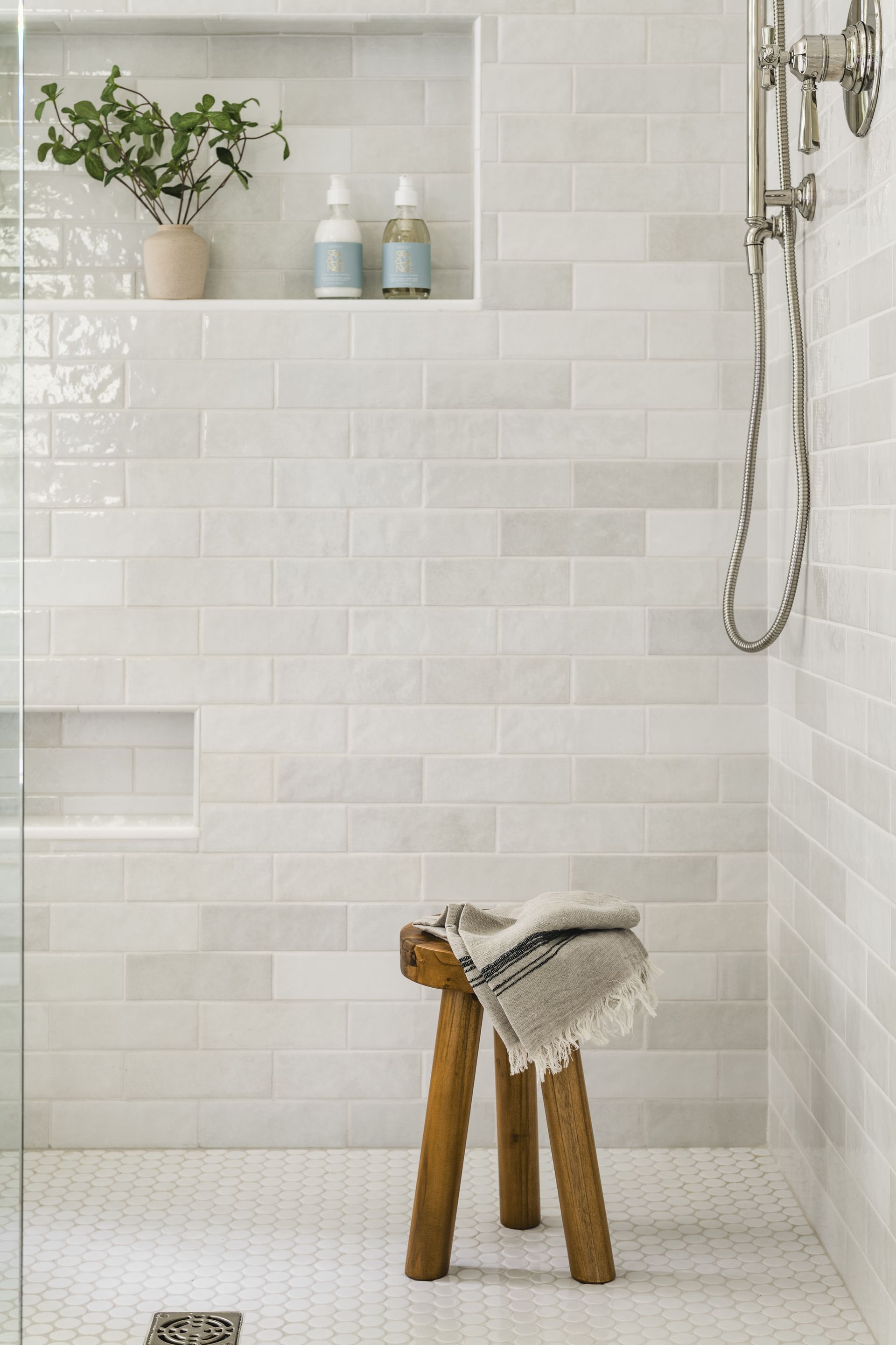There is a wooden stool in the shower with a towel on it.