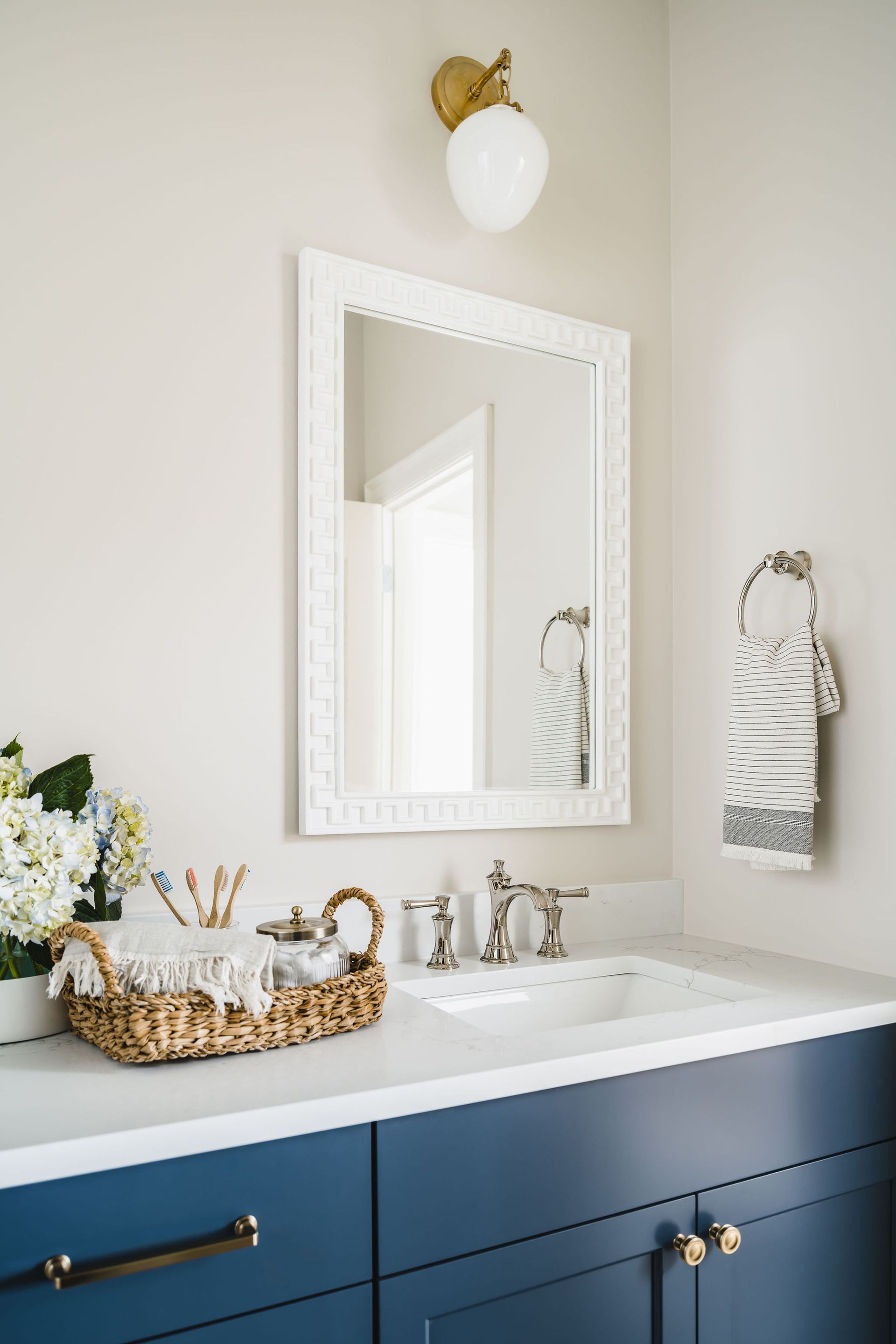 A bathroom with blue cabinets , a sink and a mirror.