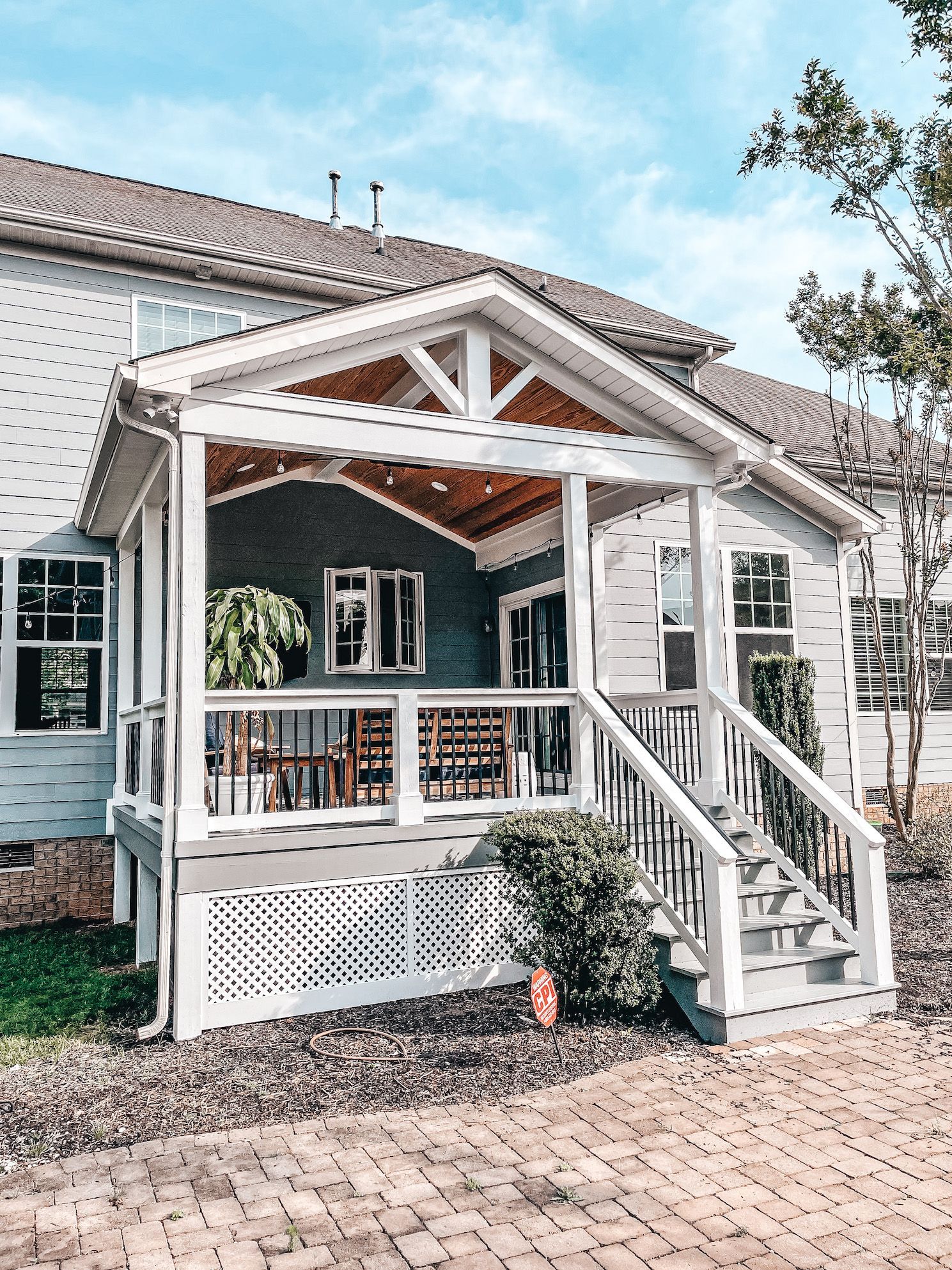 A white house with a porch and stairs in front of it.