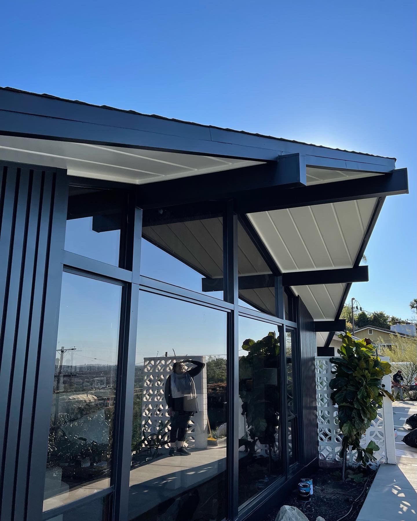 Modern building with large windows and a person reflected, blue sky.