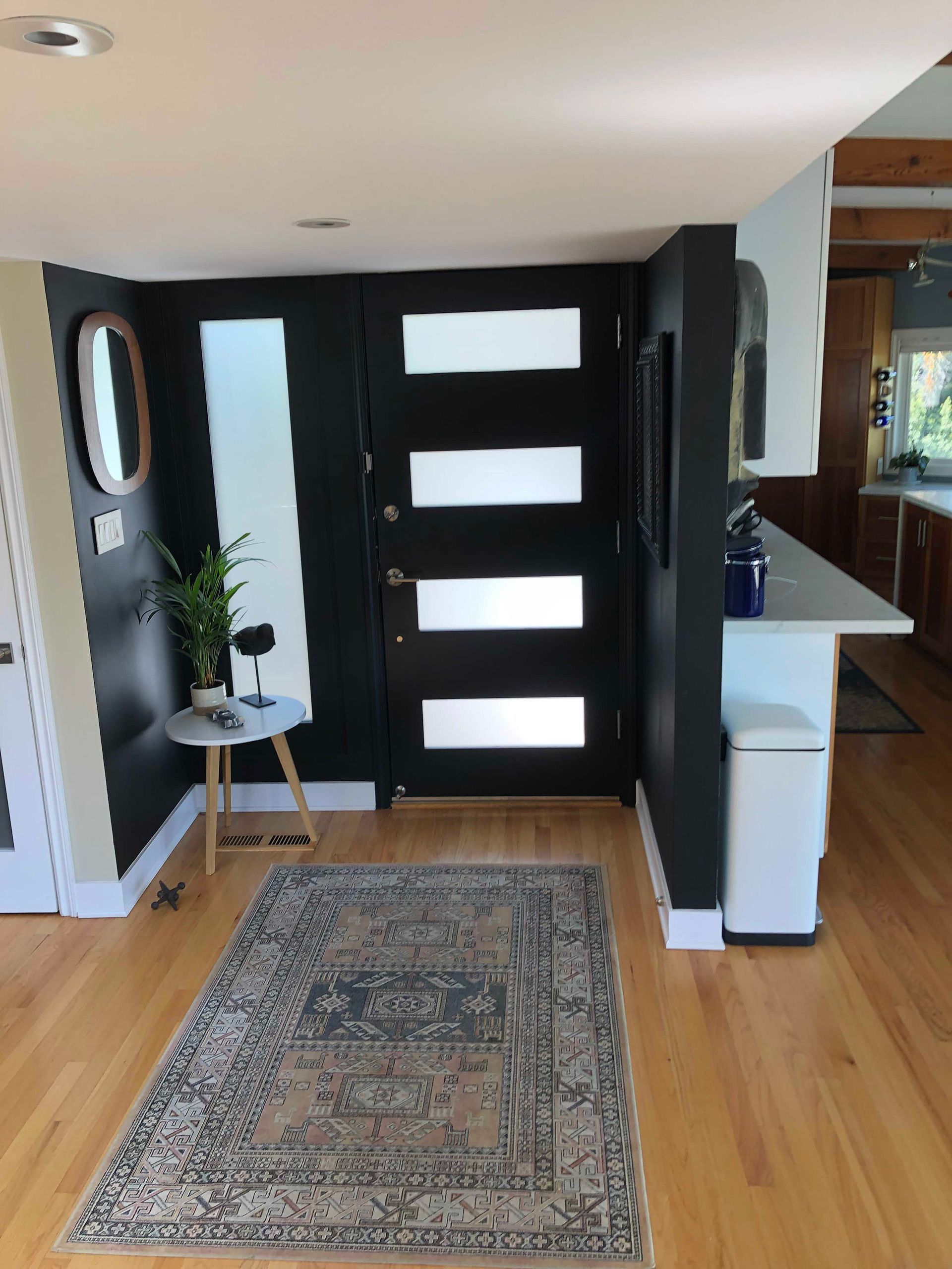 Entryway with black door, frosted glass panels, gray rug, and black accent wall.
