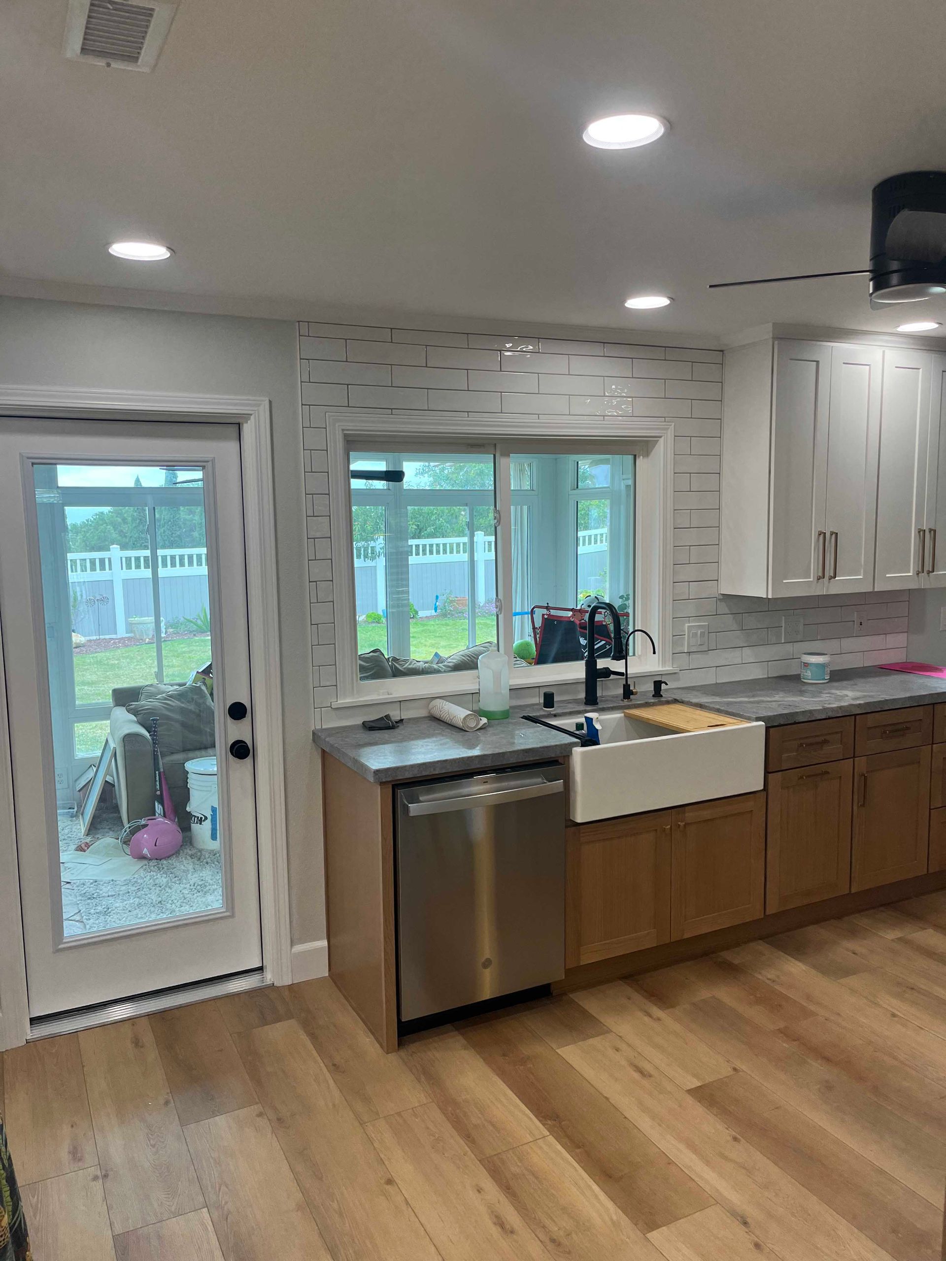 Kitchen with light wood cabinets, stainless steel appliances, and a window overlooking a yard.