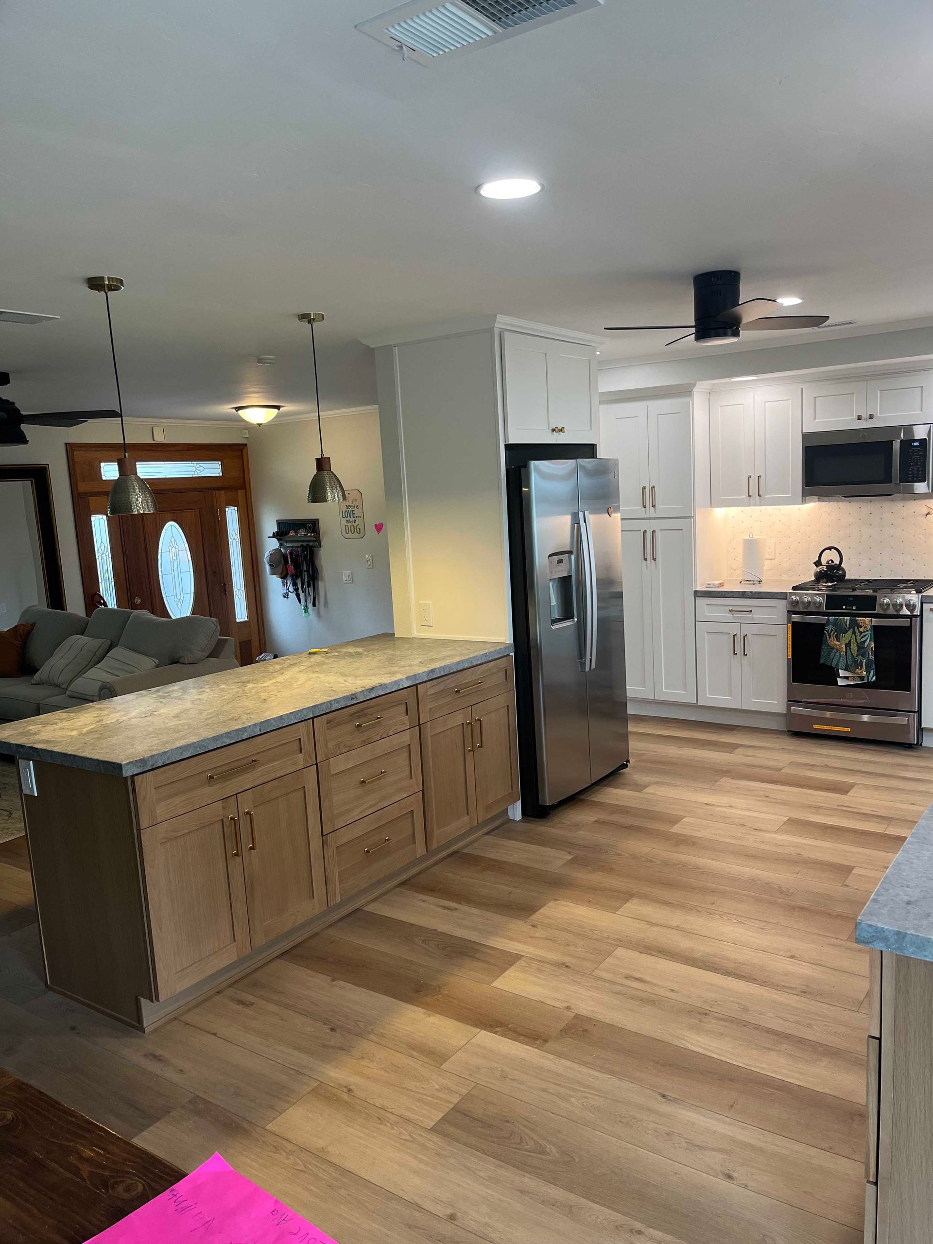 Kitchen with light-colored cabinets, a large island, stainless steel appliances, and wood-look flooring.