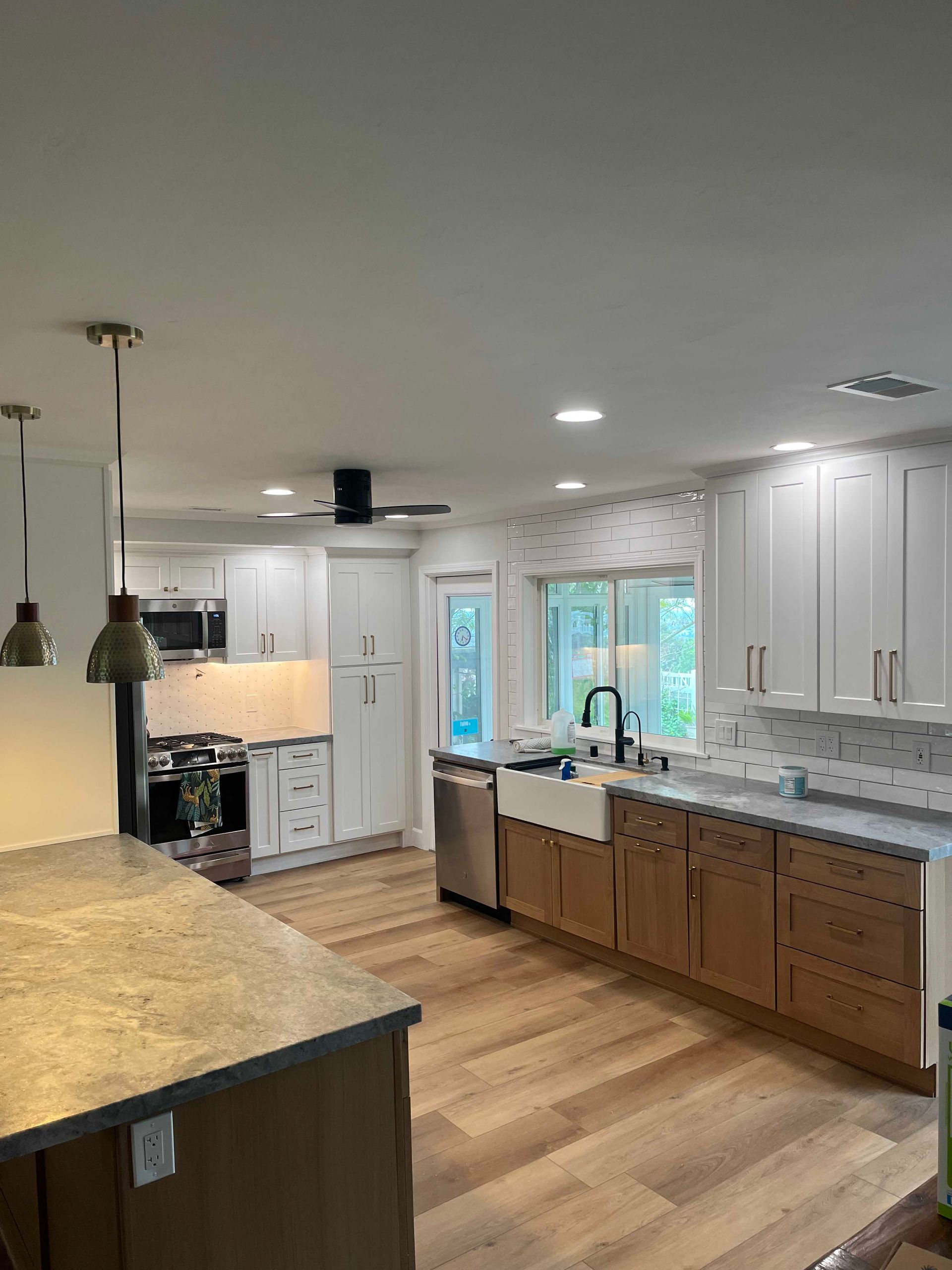 Modern kitchen remodel with white and wood cabinets, stainless appliances, and pendant lights.