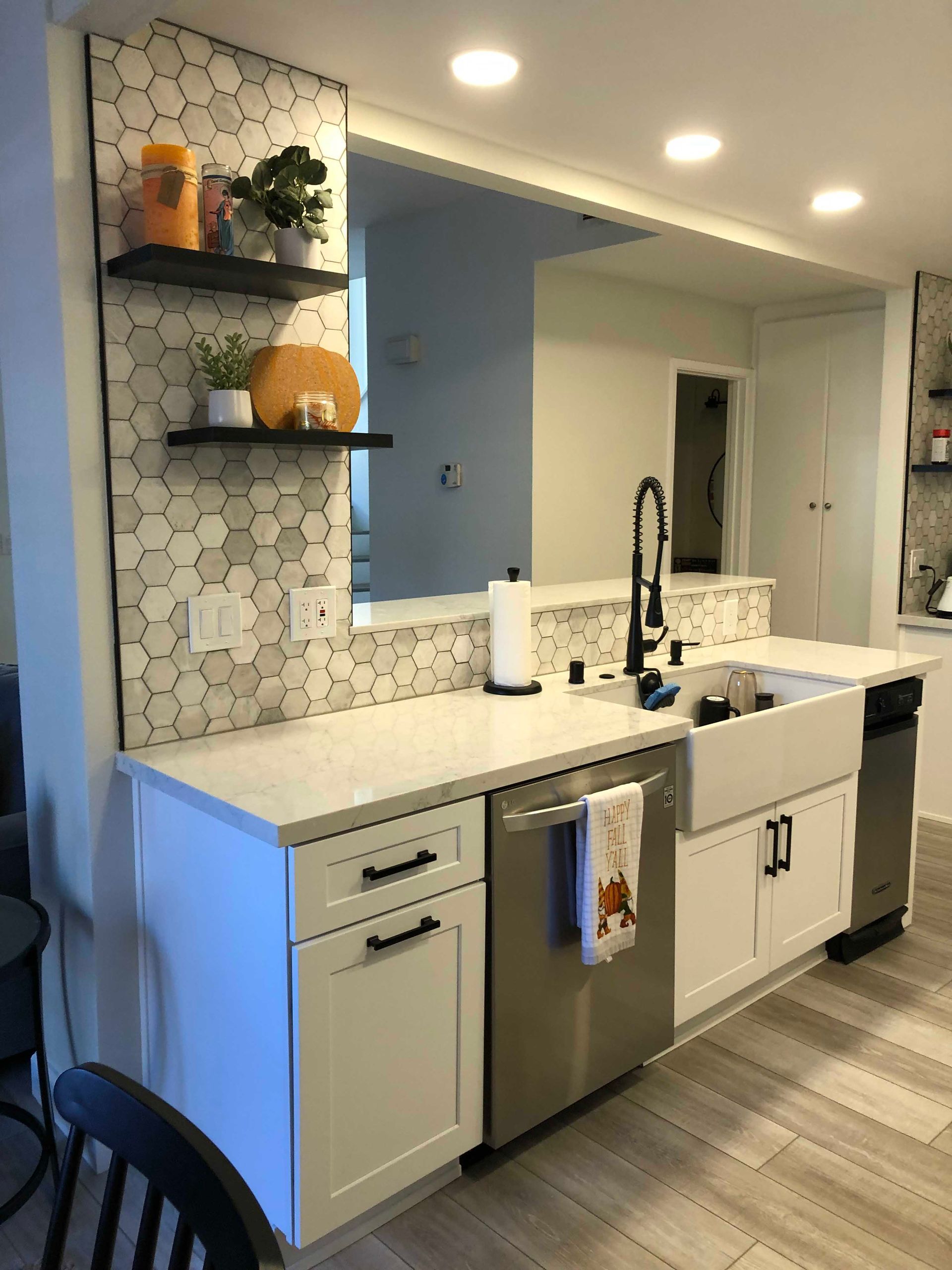 Renovated kitchen with white cabinets, stainless appliances, and a pass-through to another room.