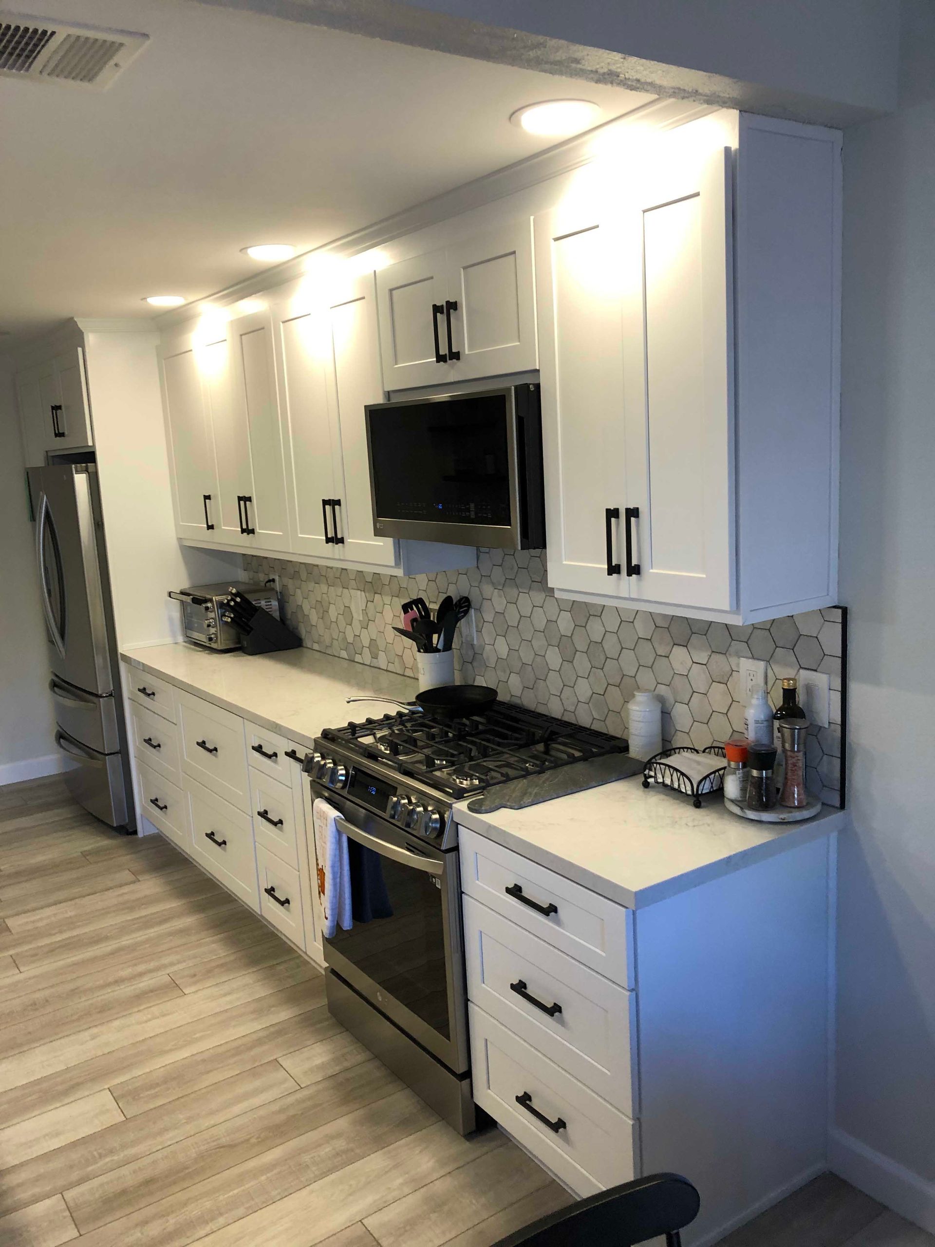 White kitchen cabinets and counters, stainless steel appliances.